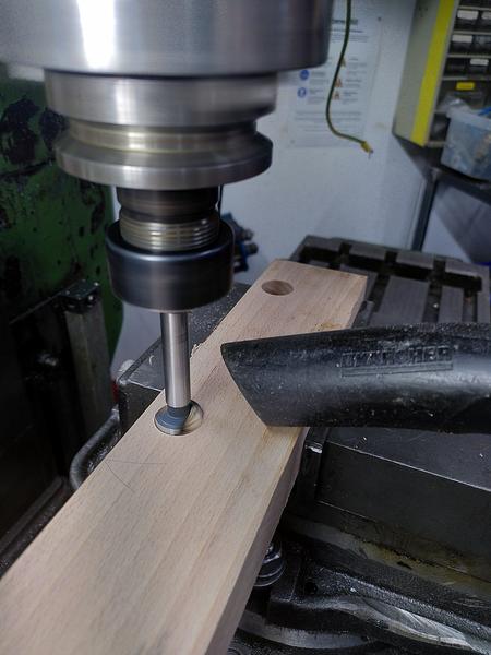 A piece of beech (fagus sylvatica) in a machinest vice on the mill. A
hole has already been drilled in the far end. nearer to the camera a 20mm
forstner bit is drilling a hole, a vacuum cleaner hose is held next to the
drill to catch the chips.